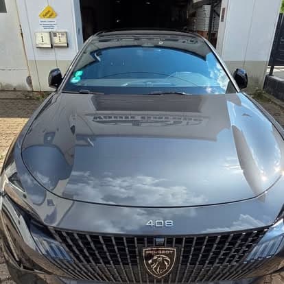 Motorhaube und Frontscheibe eines grauen Peugeot 408 spiegeln nach der Aufbereitung den Himmel.